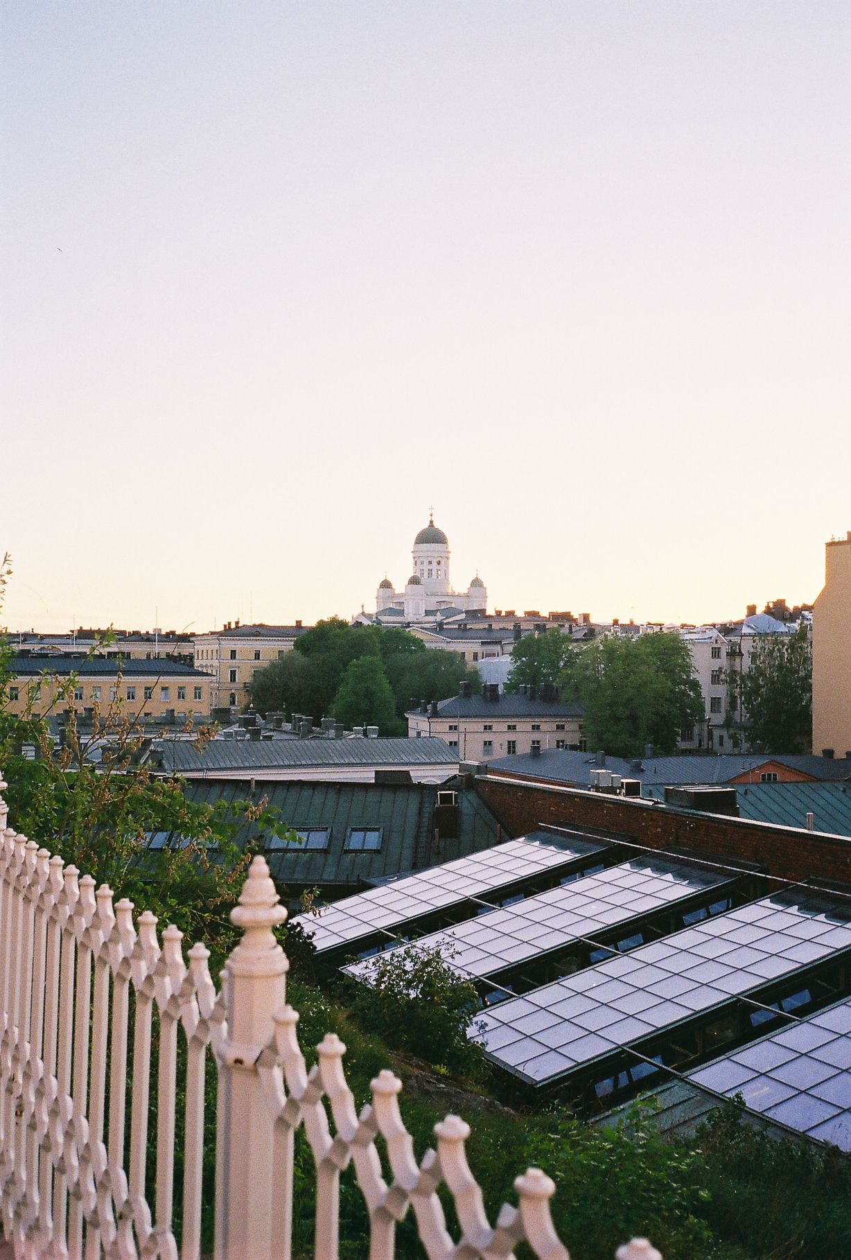 Aerial view of Helsinki cityscape at dusk with Helsinki Cathedral dome visible above rooftops and solar panels.