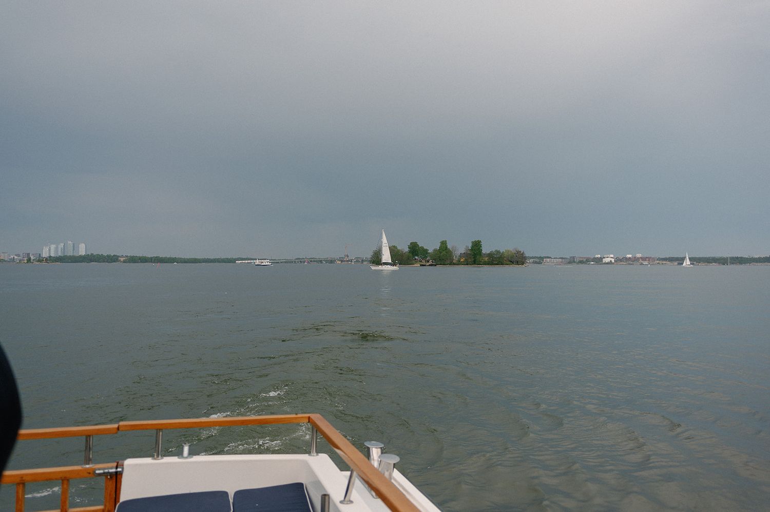 View of a sailboat on calm waters with trees visible in the distance.