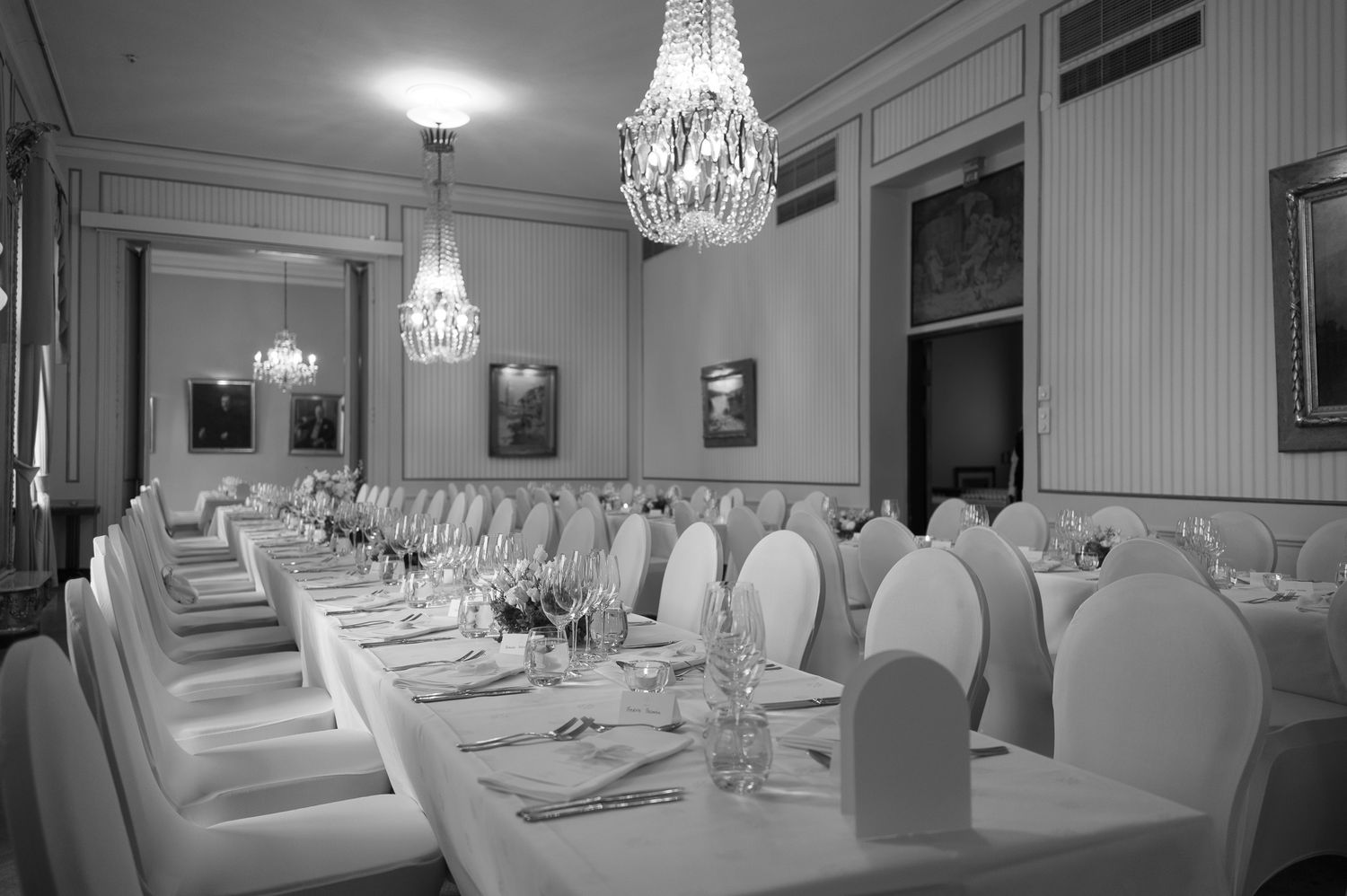 Elegant banquet hall with crystal chandeliers and white-draped tables set for a formal dining event.