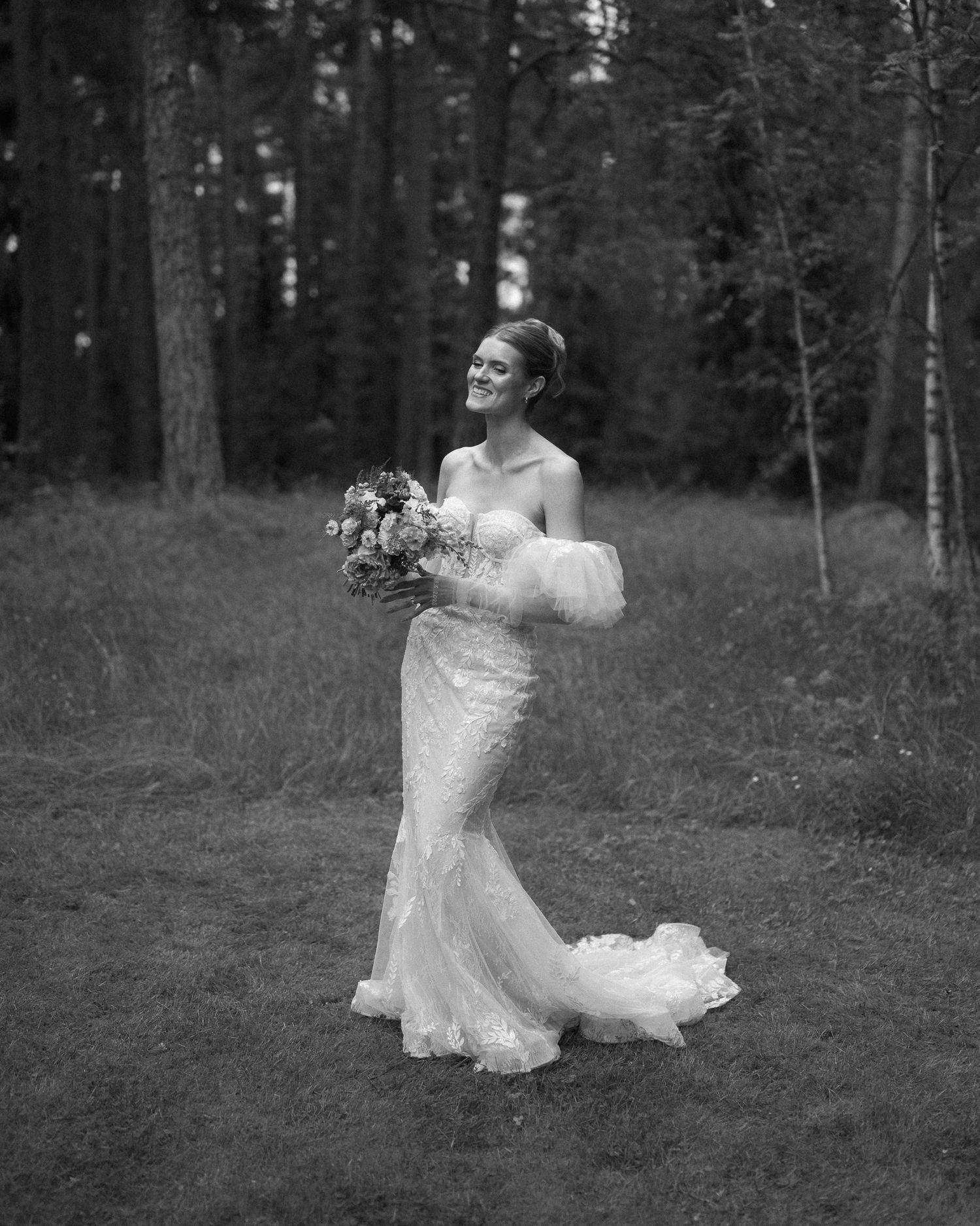 Black and white photo series of a bride twirling in a lace dress outdoors in a forest setting.