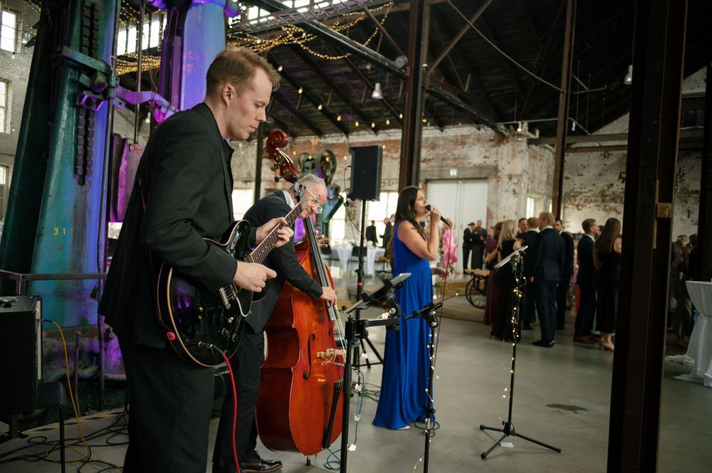 Musicians perform at a wedding reception in an industrial warehouse space.