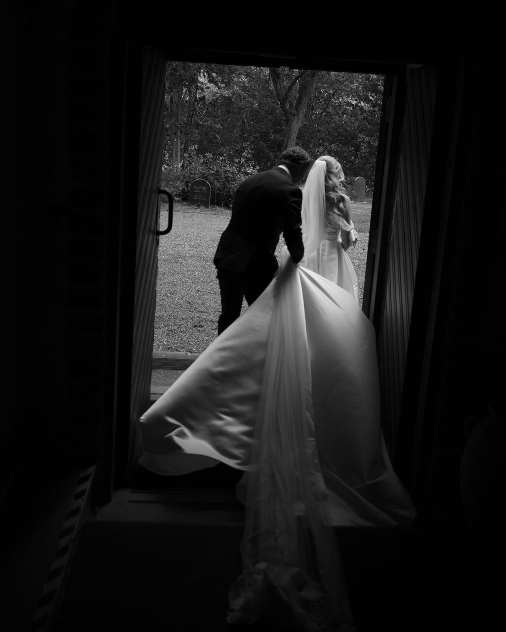Dramatic silhouette of a wedding dress through a doorway.