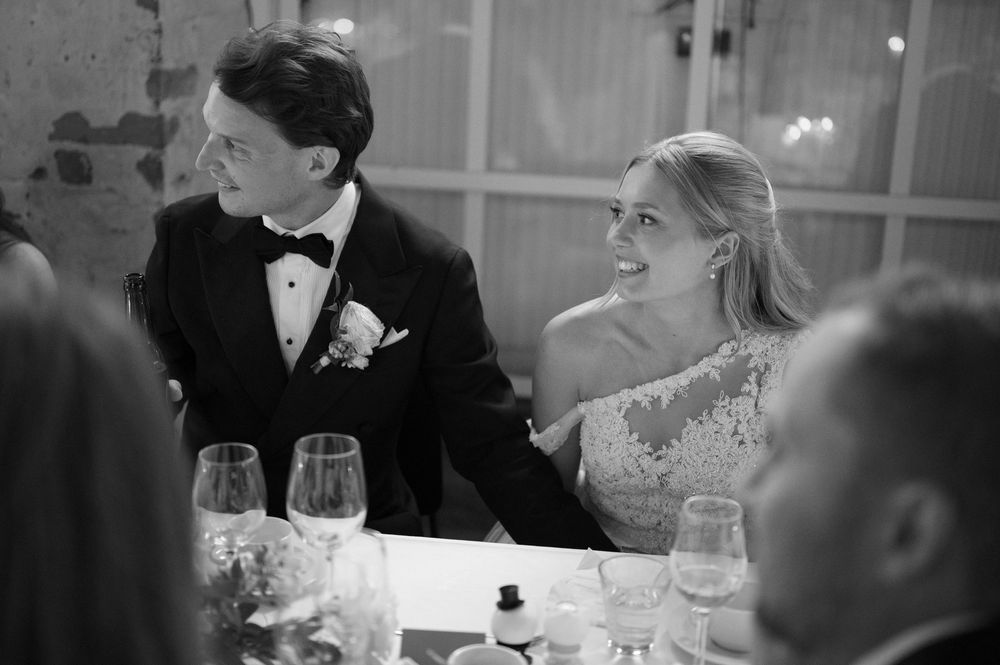 Wedding reception dinner scene with formal place settings and glassware on white tablecloths.