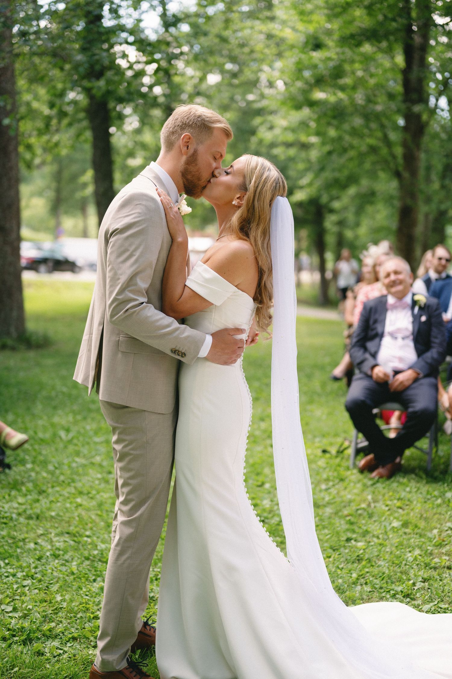 Romantic wedding moment captured in a lush green outdoor garden setting.