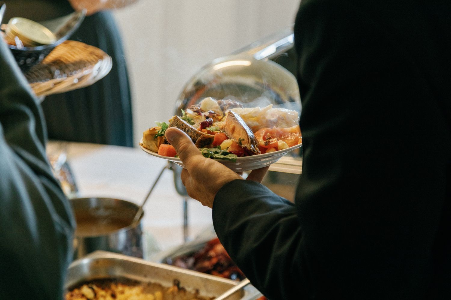 People serving themselves from platters at an elegant buffet station.