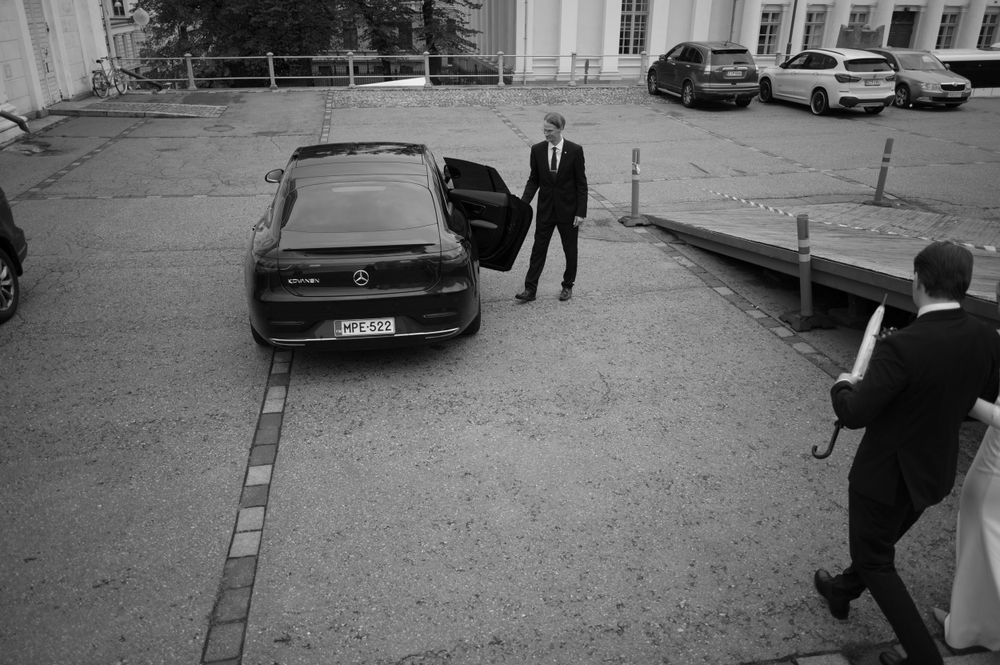 Black cars parked outside a building with people walking in formal attire.