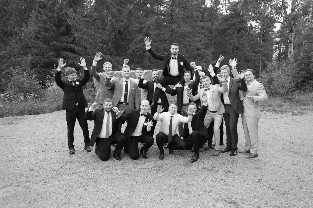 Black and white photo of groomsmen jumping in celebration outdoors.