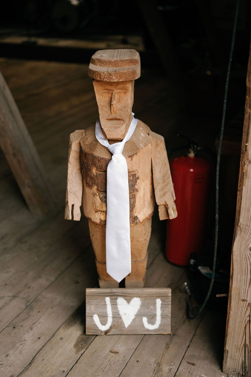 Wooden folk art figure wearing a white tie displayed on rustic wooden surface.