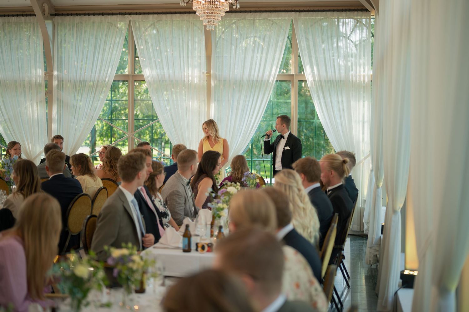 Wedding reception venue with white draped fabric and chandelier decorations.
