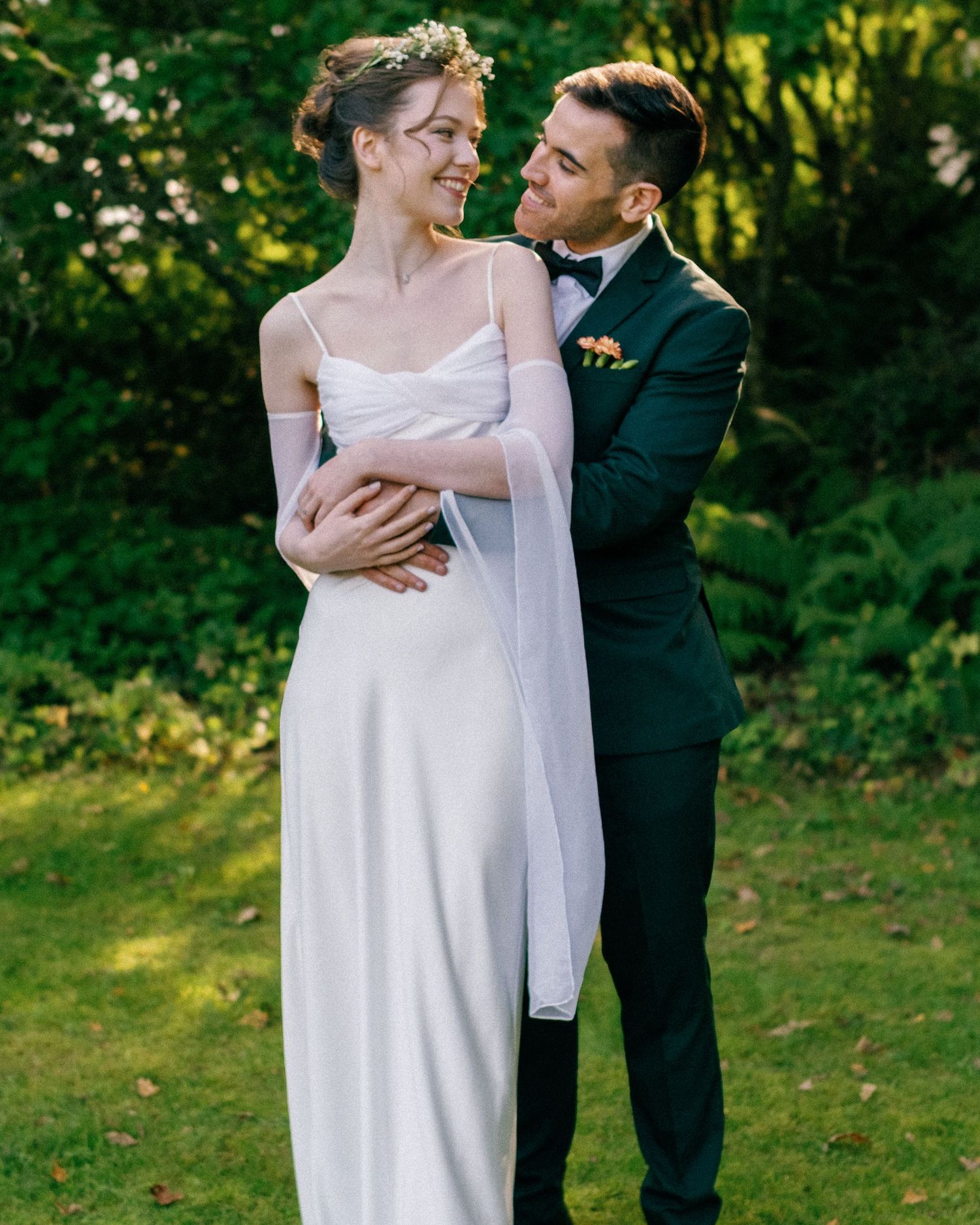 Tender wedding moments photographed against lush green garden backdrop.