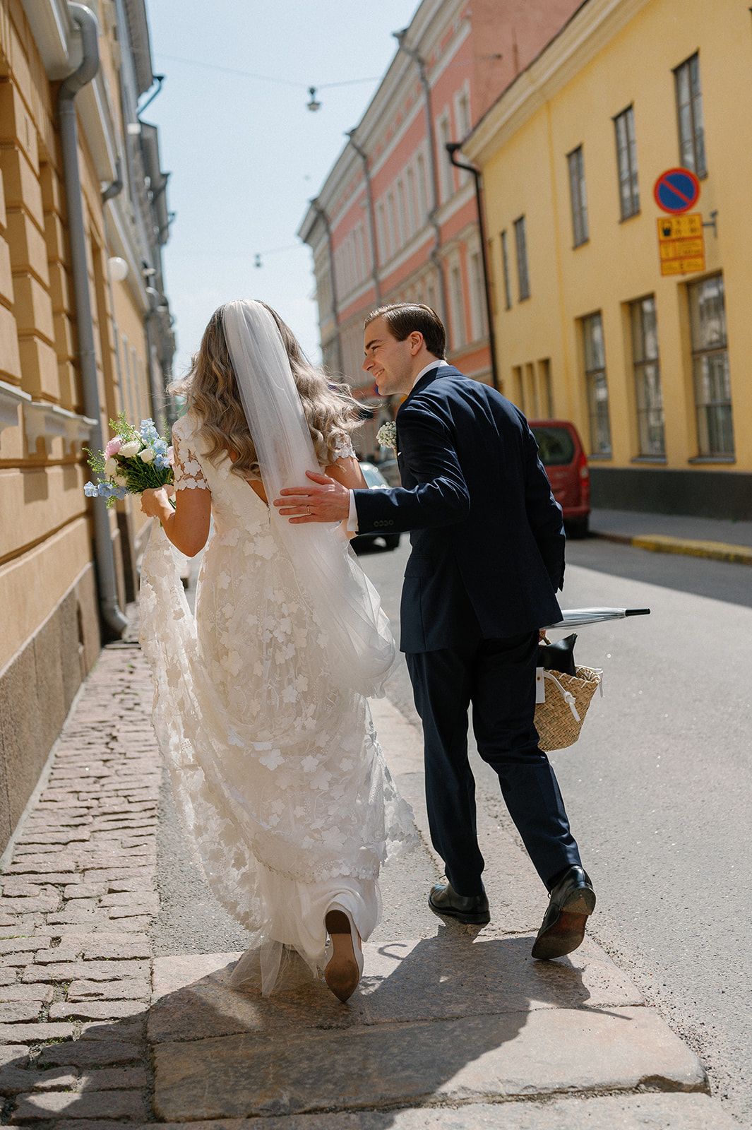 Wedding couple walking on cobblestone street in an old European city.