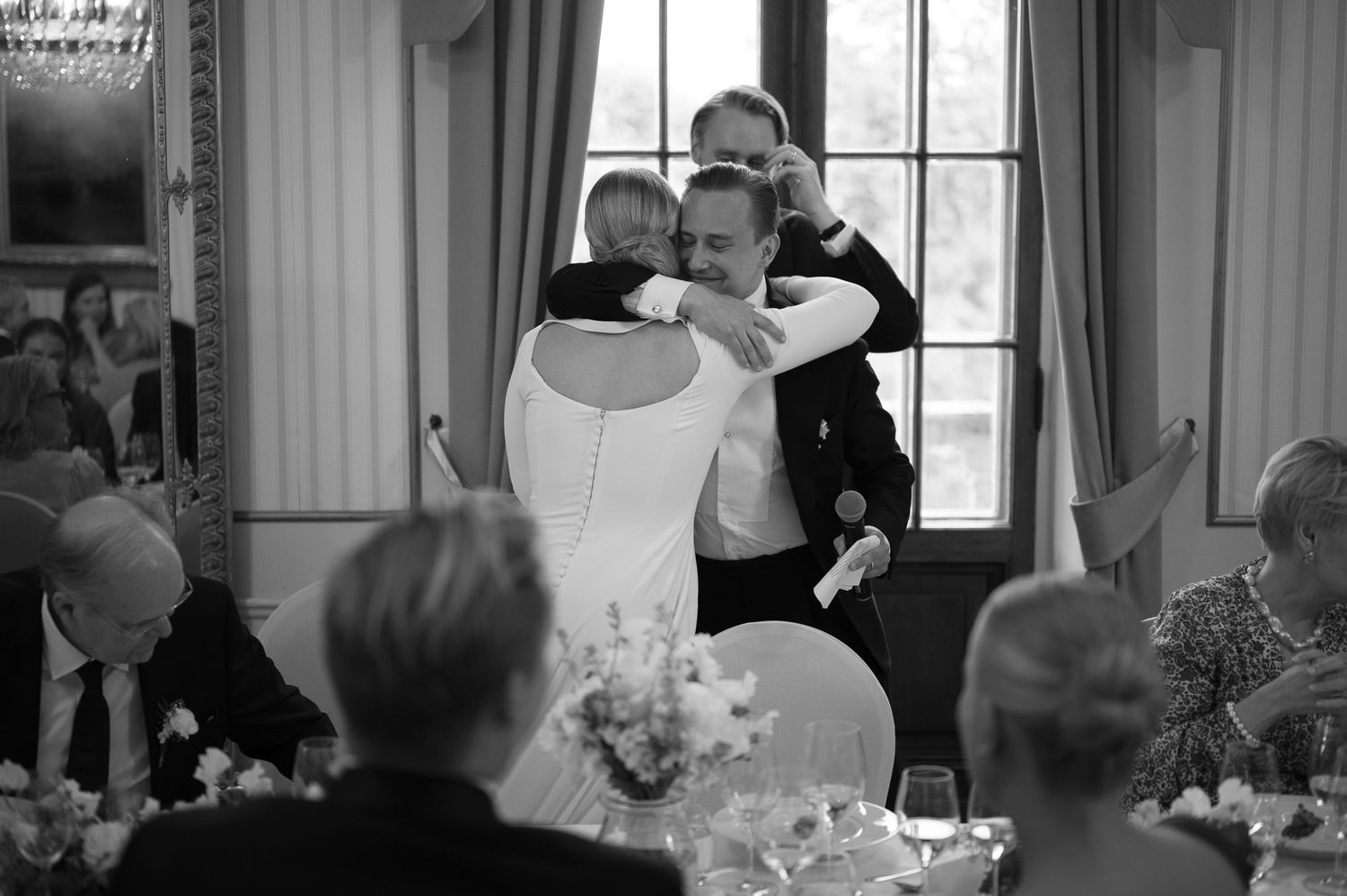 Black and white wedding ceremony photos showing intimate moments between couples and guests in an elegant venue.