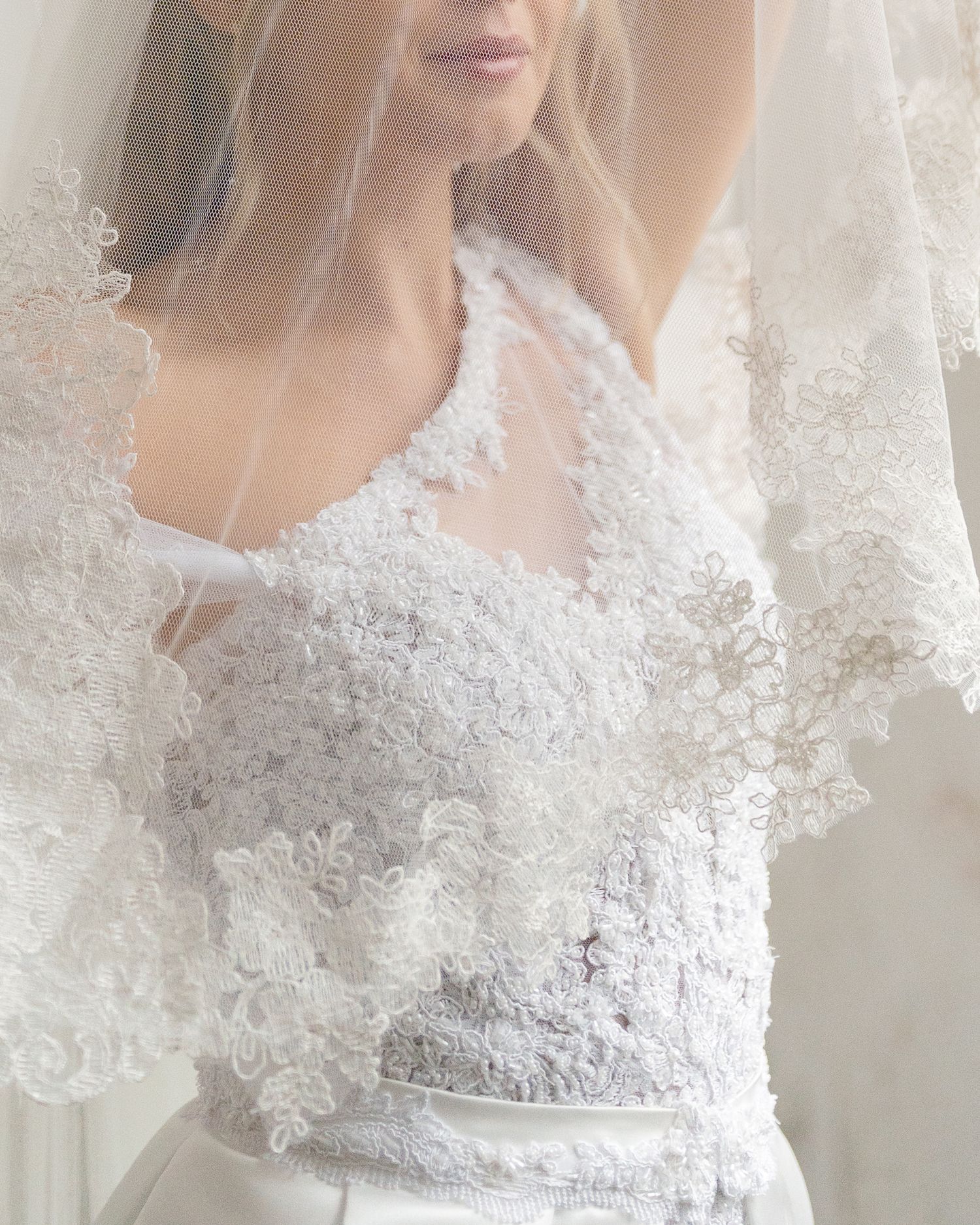 Close-up detail of a white lace wedding dress with delicate floral appliques.
