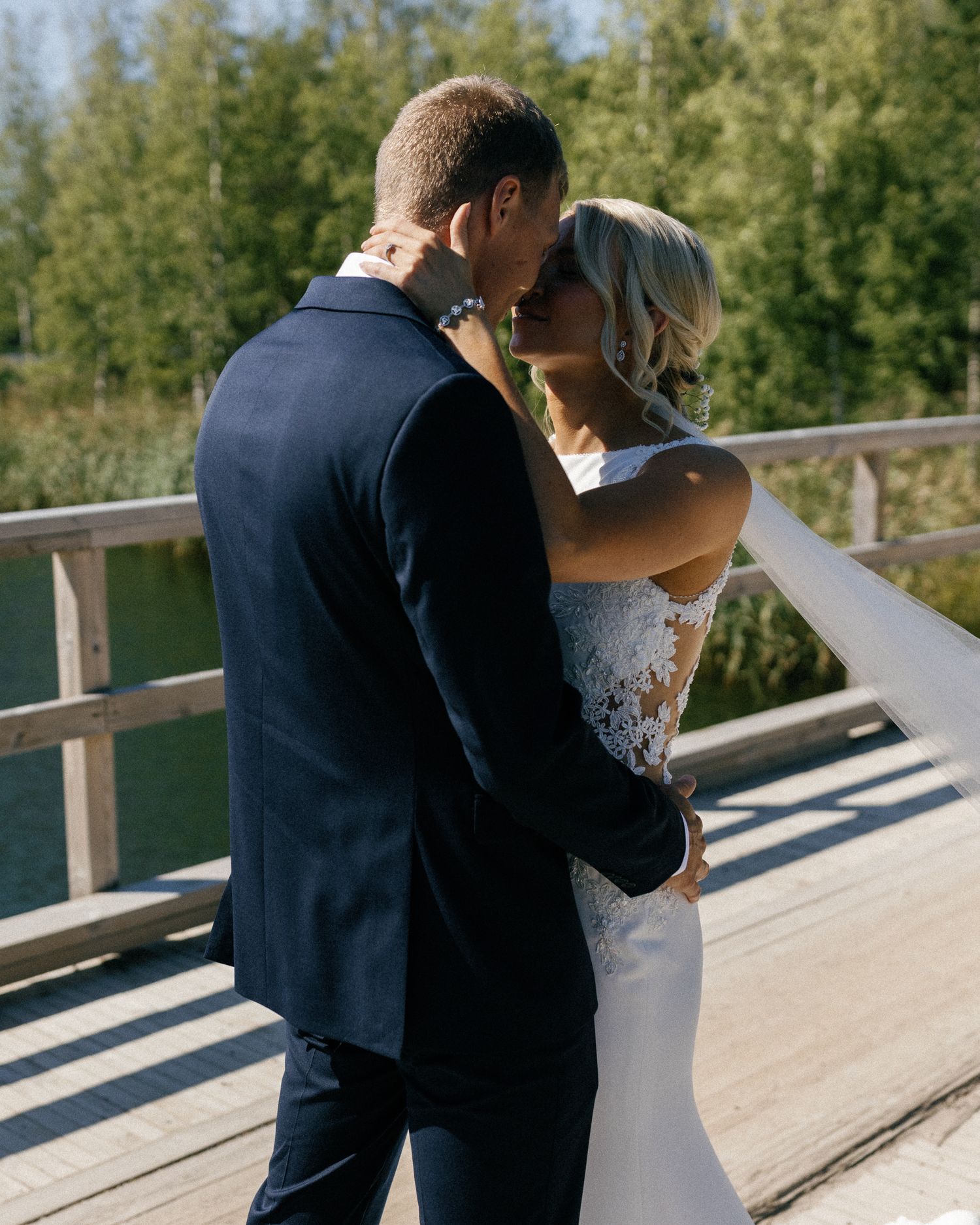 Romantic wedding moment captured on a sunlit wooden boardwalk.