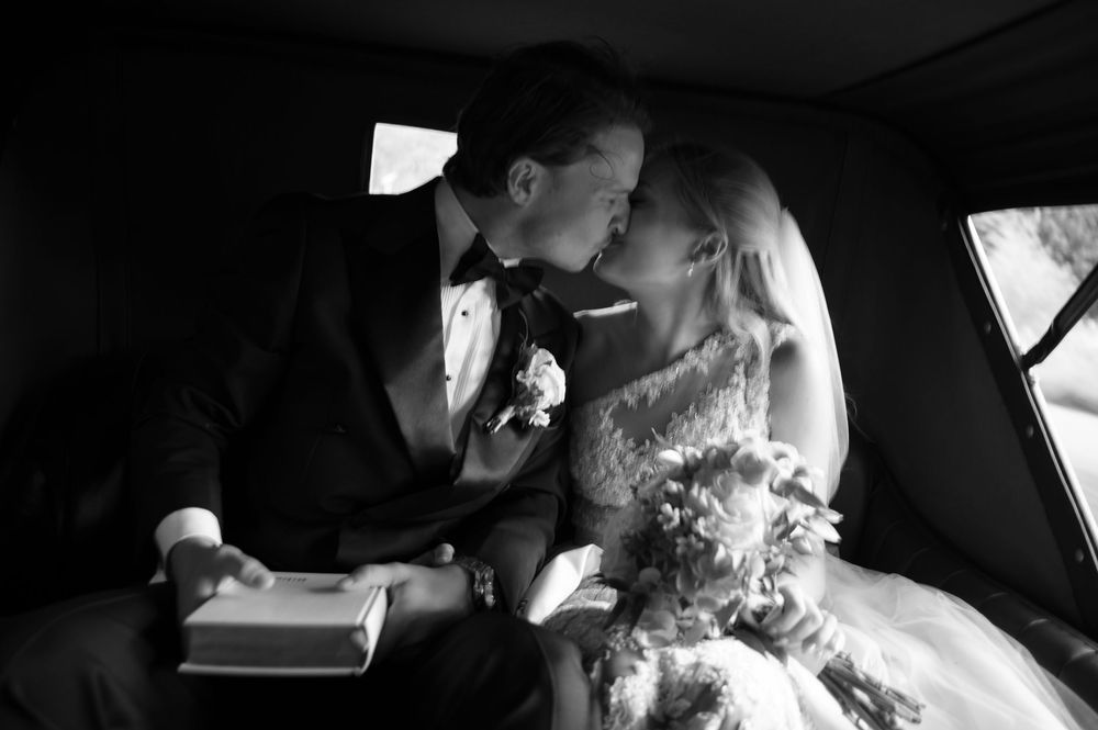 Black and white photo capturing candid moments in wedding car.