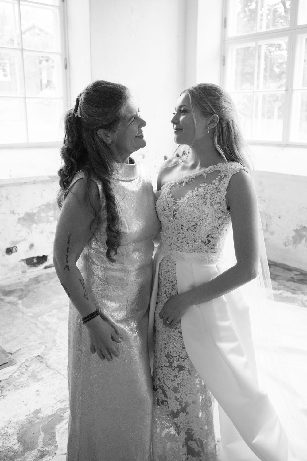 Black and white photos showing tender moments between two women in elegant dresses at a wedding celebration.