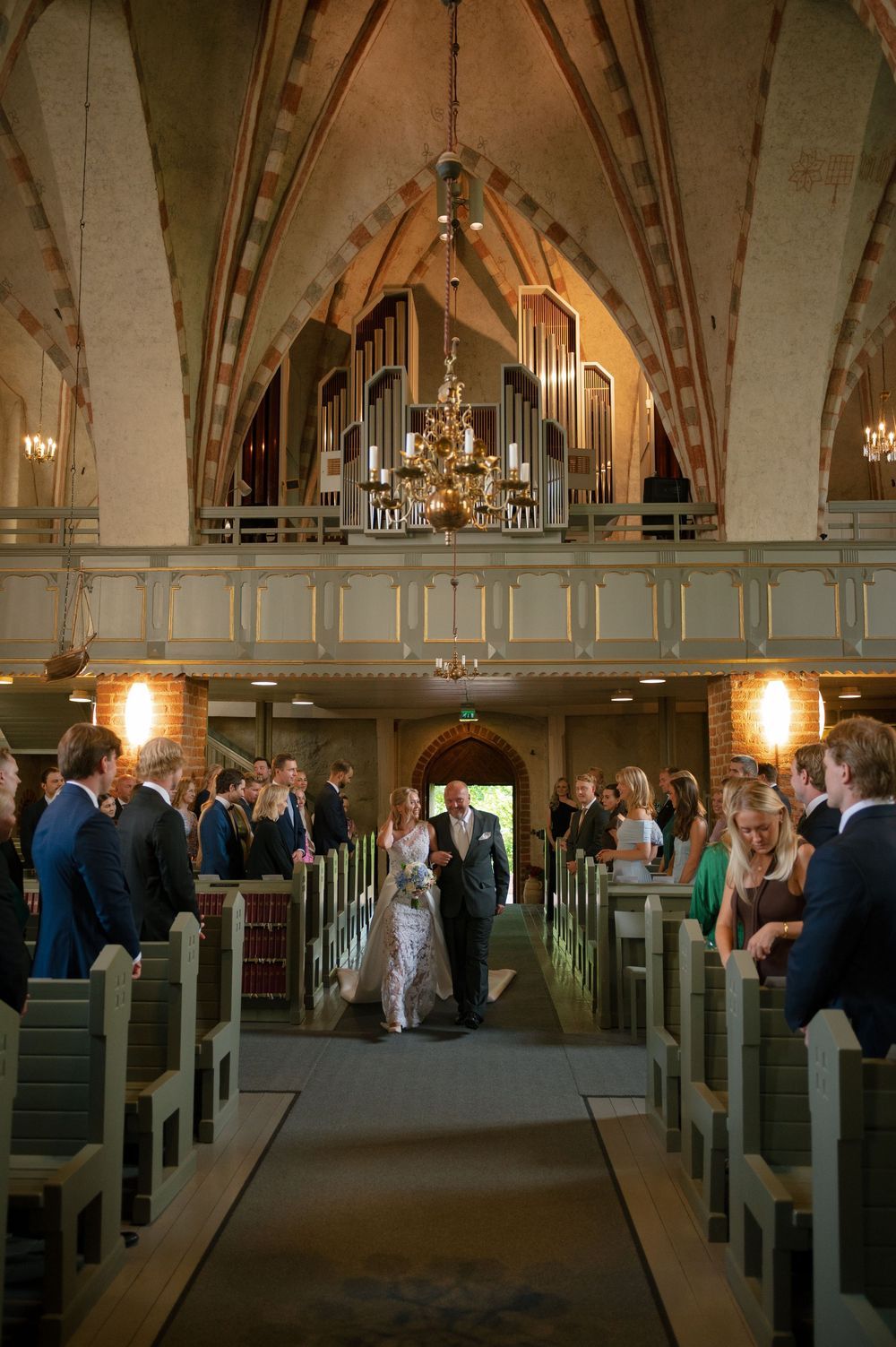 Interior view of a historic church sanctuary with vaulted ceilings and wooden pews during a wedding.