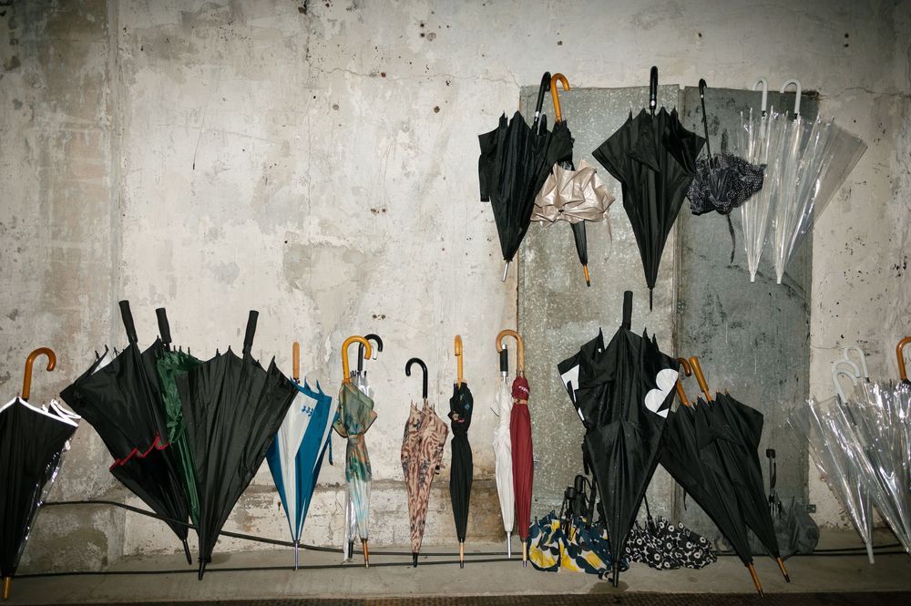 A collection of black umbrellas arranged against a white wall creates an artistic display at a wedding venue.