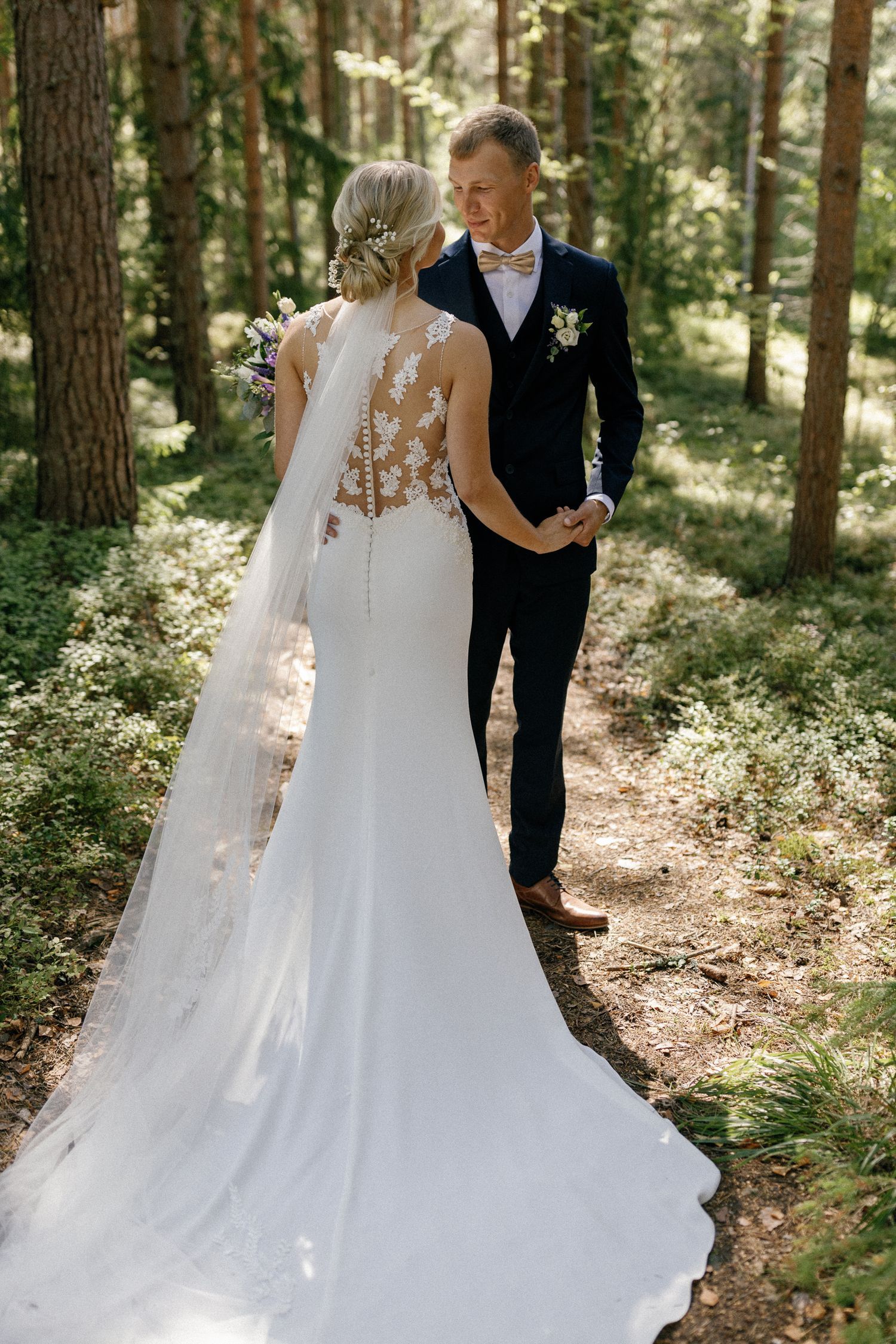 Elegant wedding dress with lace details captured in forest setting.