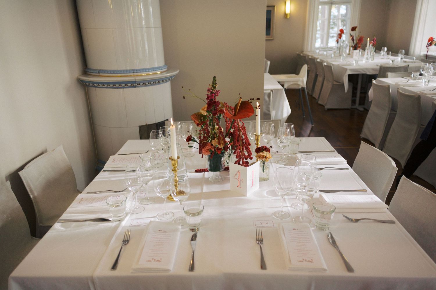 Elegant restaurant interior with white tablecloths, place settings, and warm lighting creating an upscale dining atmosphere.