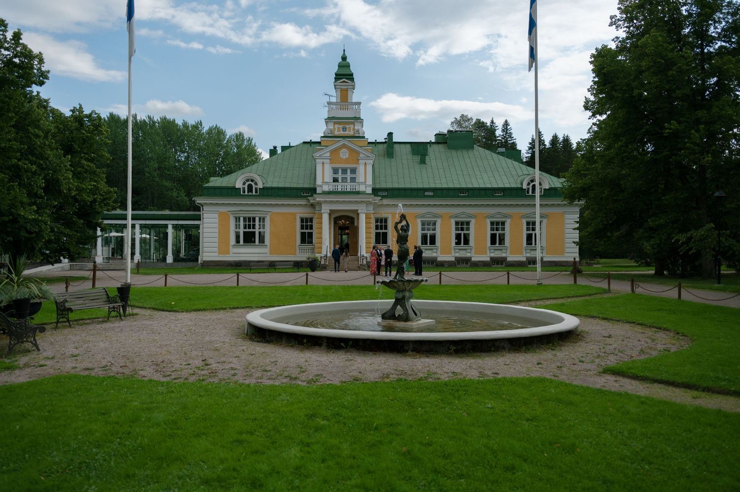Panoramic view of a grand estate with manicured lawns and classical architecture under blue skies.