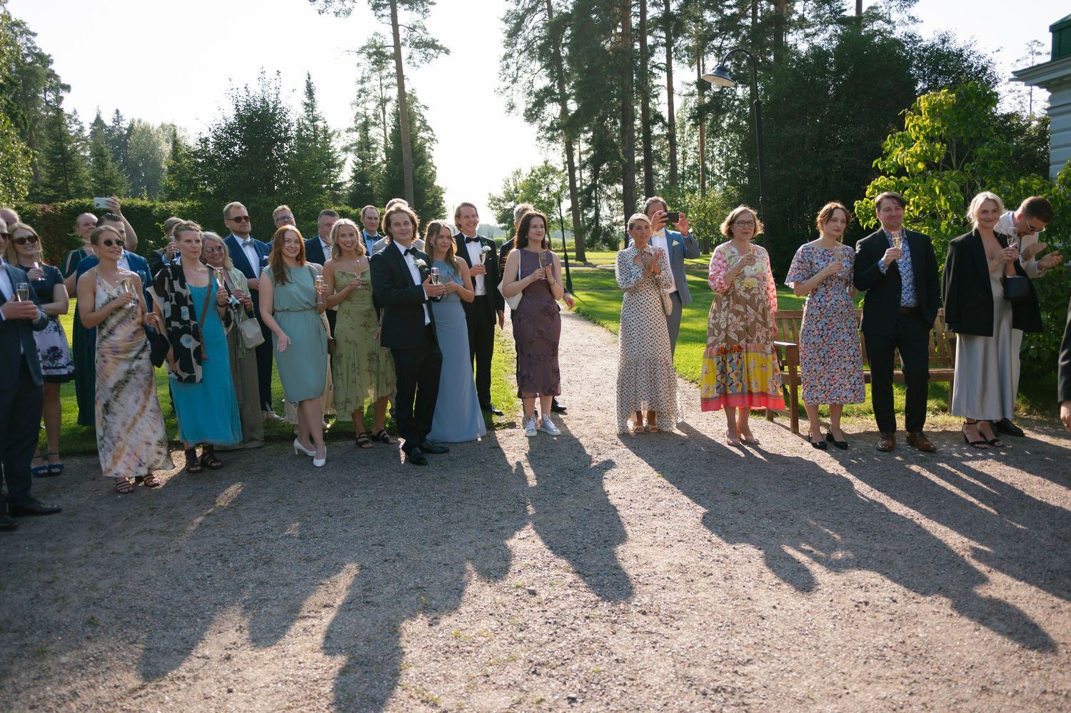 Large group of wedding guests posed together outdoors in natural setting.