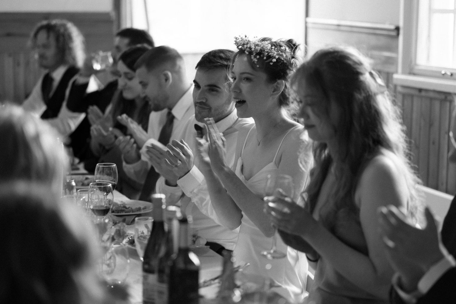 Wedding guests raise their glasses in a toast during an indoor reception celebration.