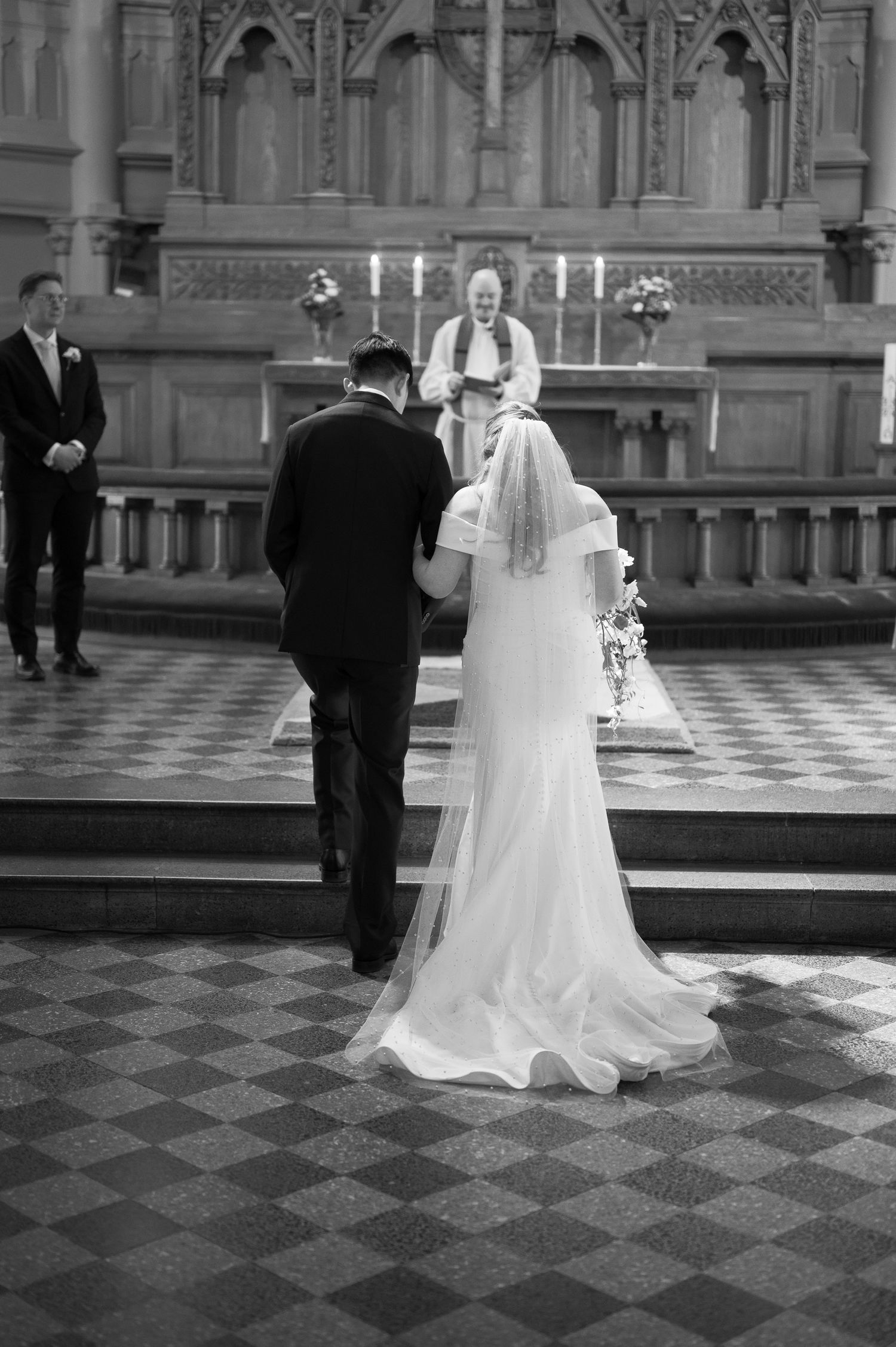 Black and white photo of a bride and groom standing at the altar during a church wedding ceremony.