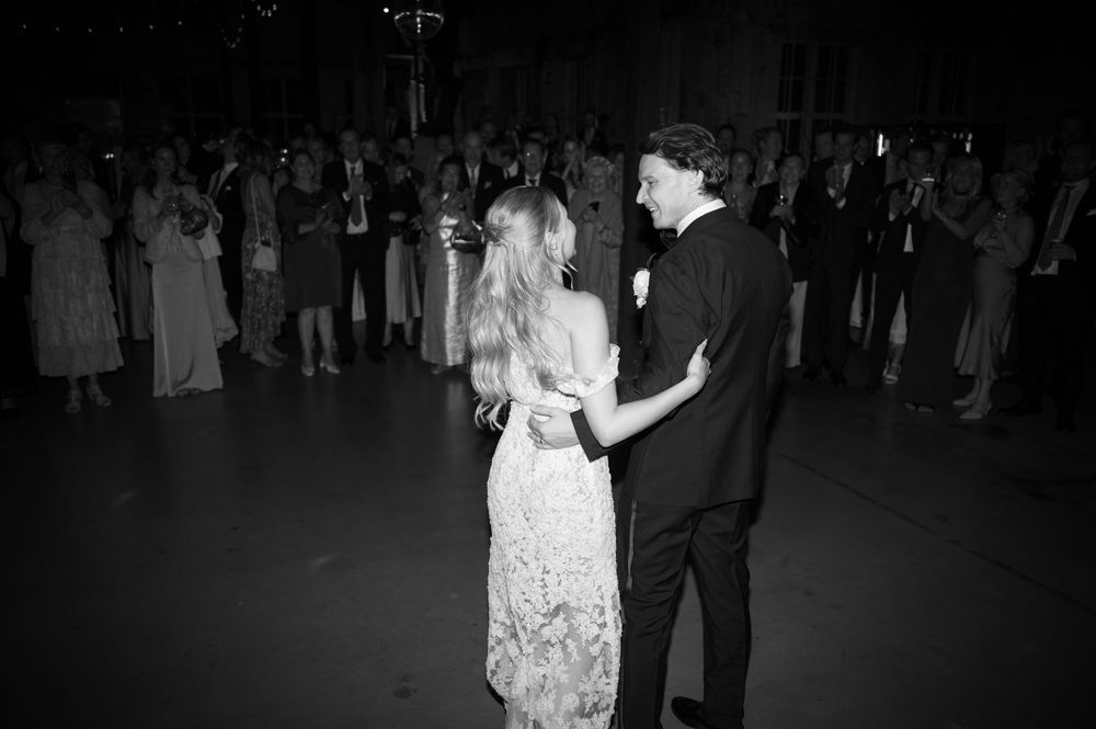 A couple shares a romantic dance moment in a dark industrial venue with onlookers.