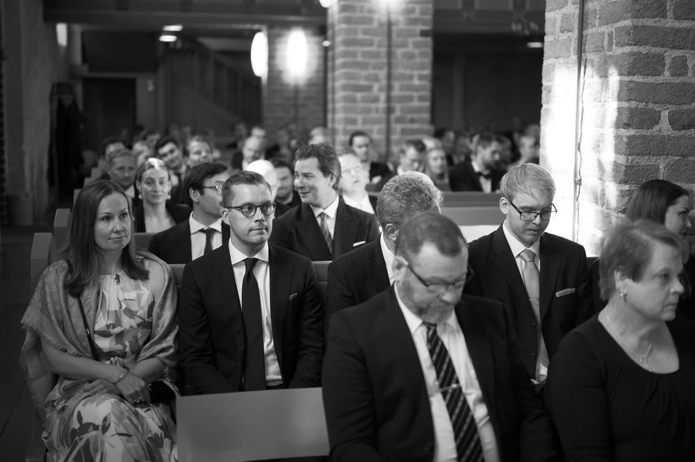 Wedding guests in formal attire walking through a church hallway.