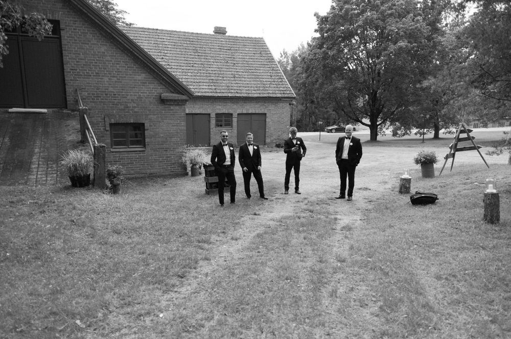 Wide shots of wedding party gathered outside rustic brick building.