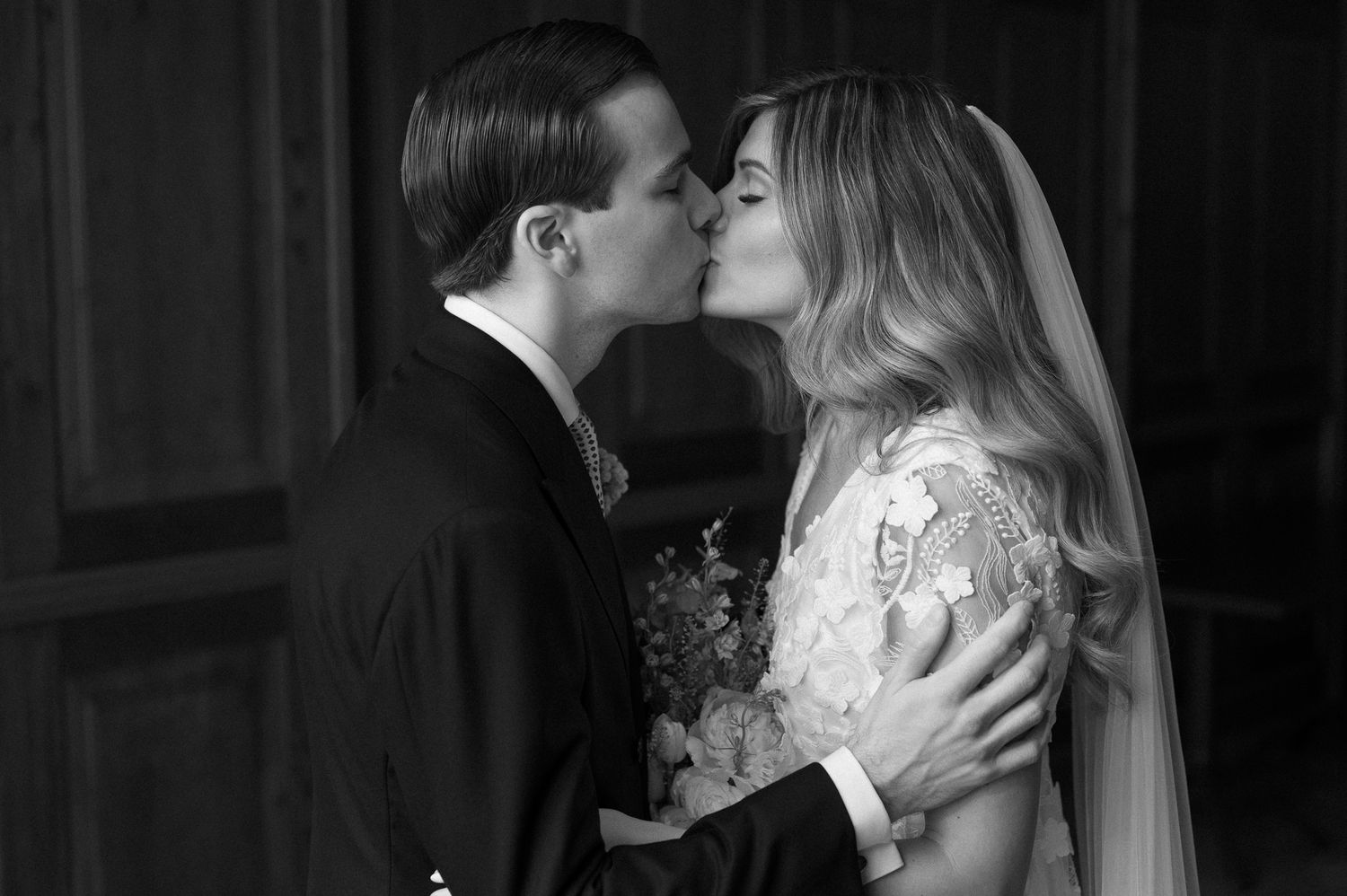 An intimate black and white portrait captures a romantic wedding moment.
