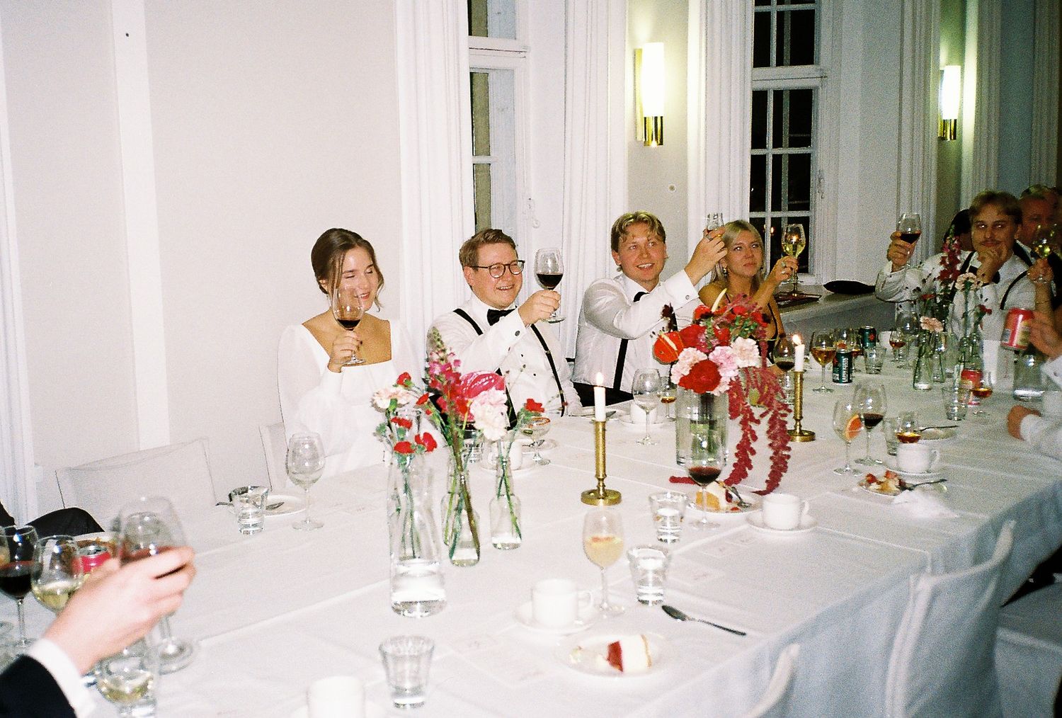 Long banquet table set for formal dinner with white linens and floral centerpieces.