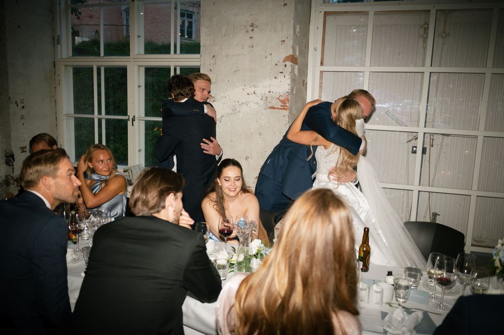 Wedding celebration in a rustic industrial space with guests mingling at decorated tables.