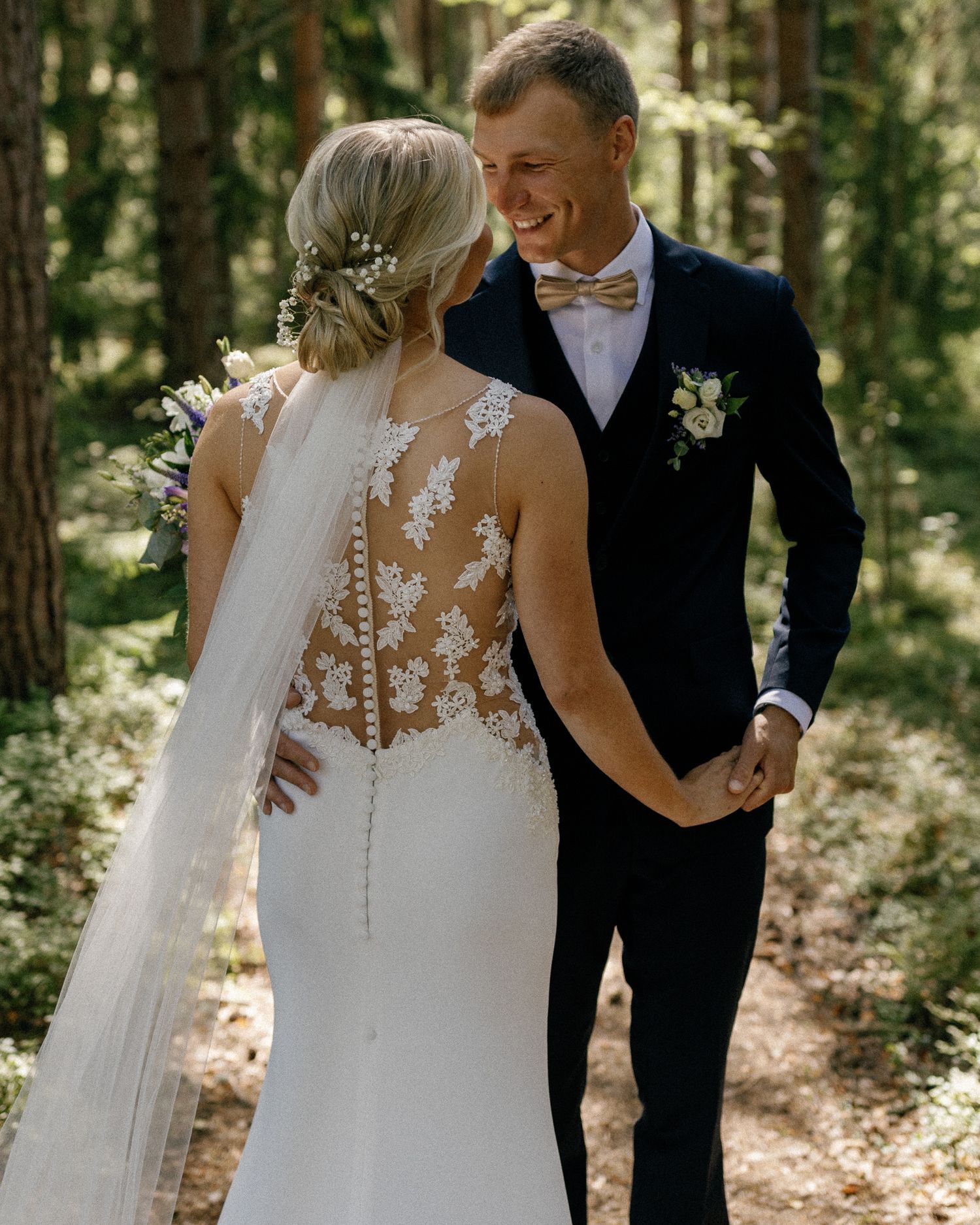 Wedding couple shares intimate moments in sunlit forest setting.