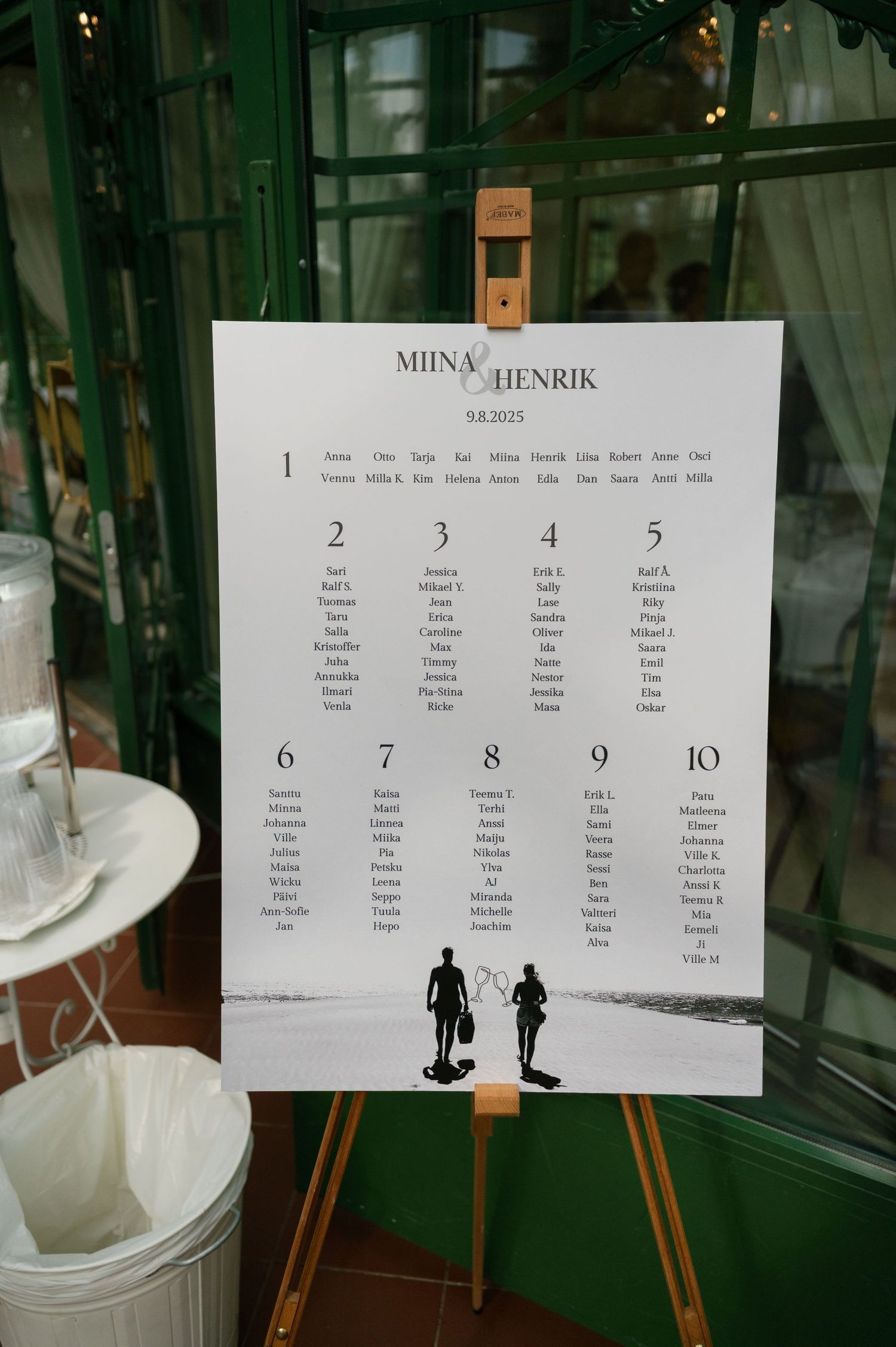 Wedding seating chart display with table assignments and silhouette decorations.