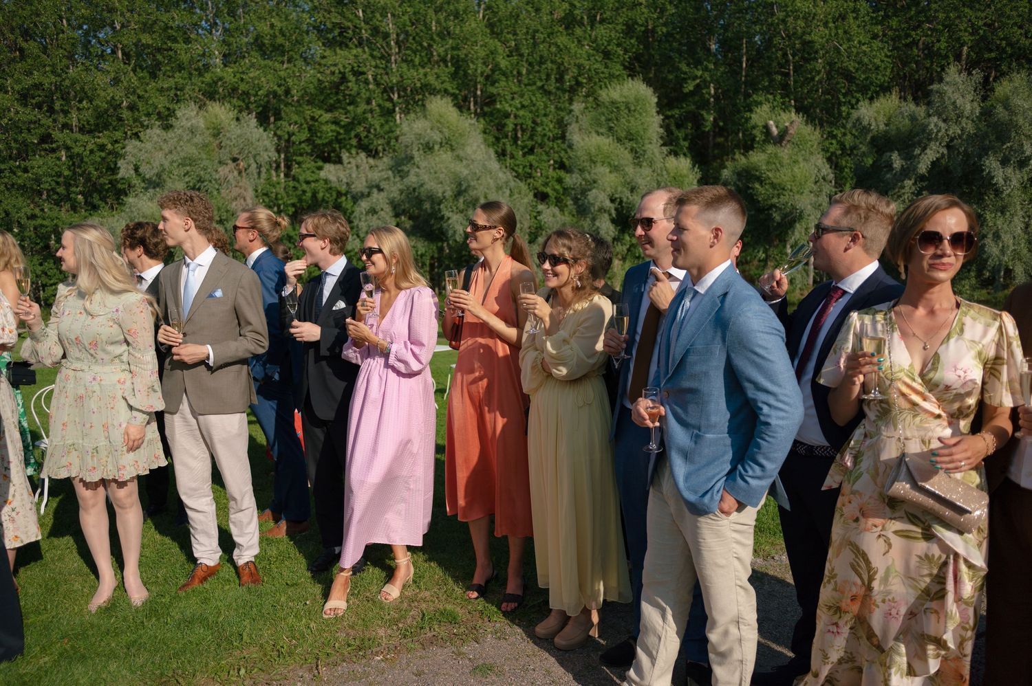 Wedding guests mingling on lawn during outdoor summer celebration.