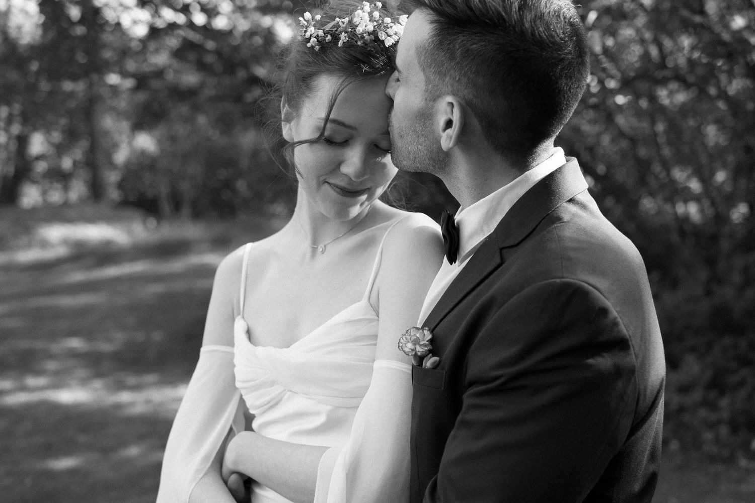 Black and white wedding portraits capturing intimate moments between newlyweds outdoors.