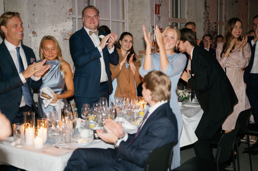 Wedding reception guests enjoying dinner and conversation at elegantly set tables with candlelight.