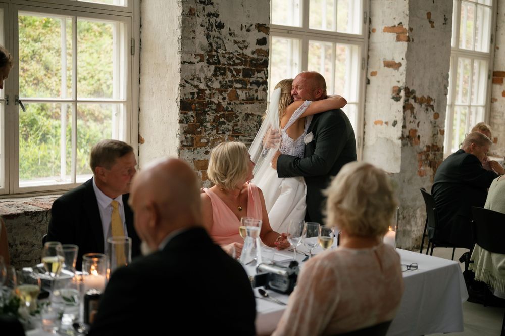 Natural light streams through windows in rustic brick venue during wedding reception.