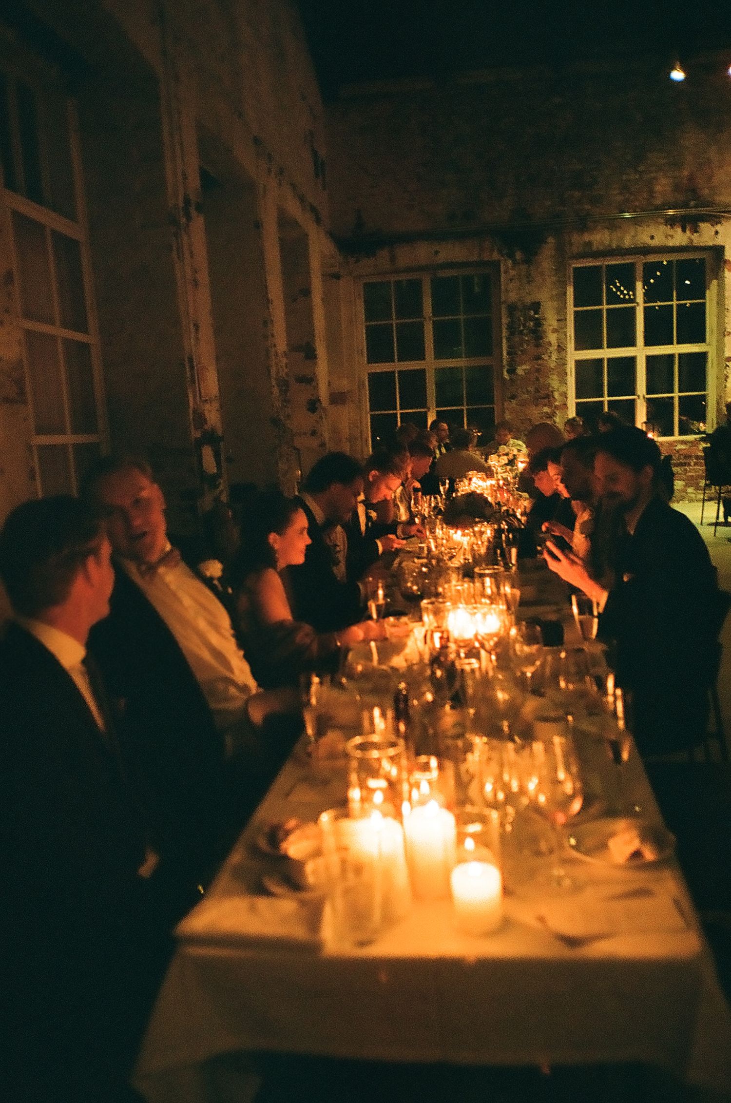Candlelit wedding reception tables creating a warm ambiance in a rustic brick venue.