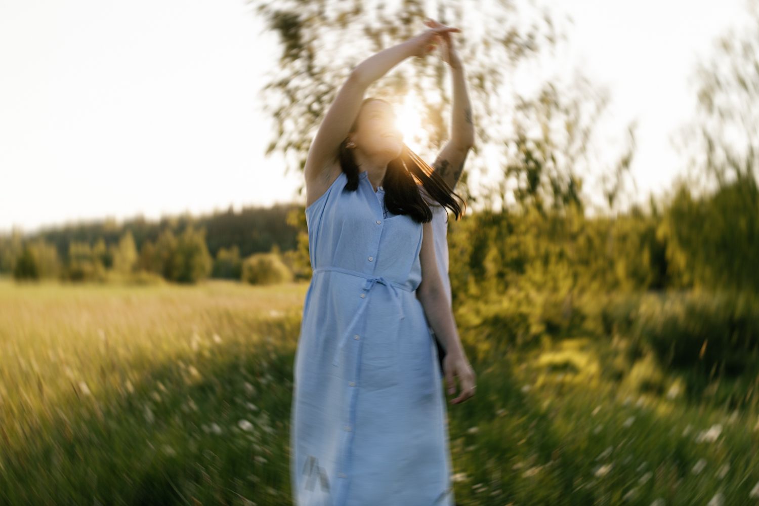 A couple embraces in a sunny field with tall grass during golden hour.