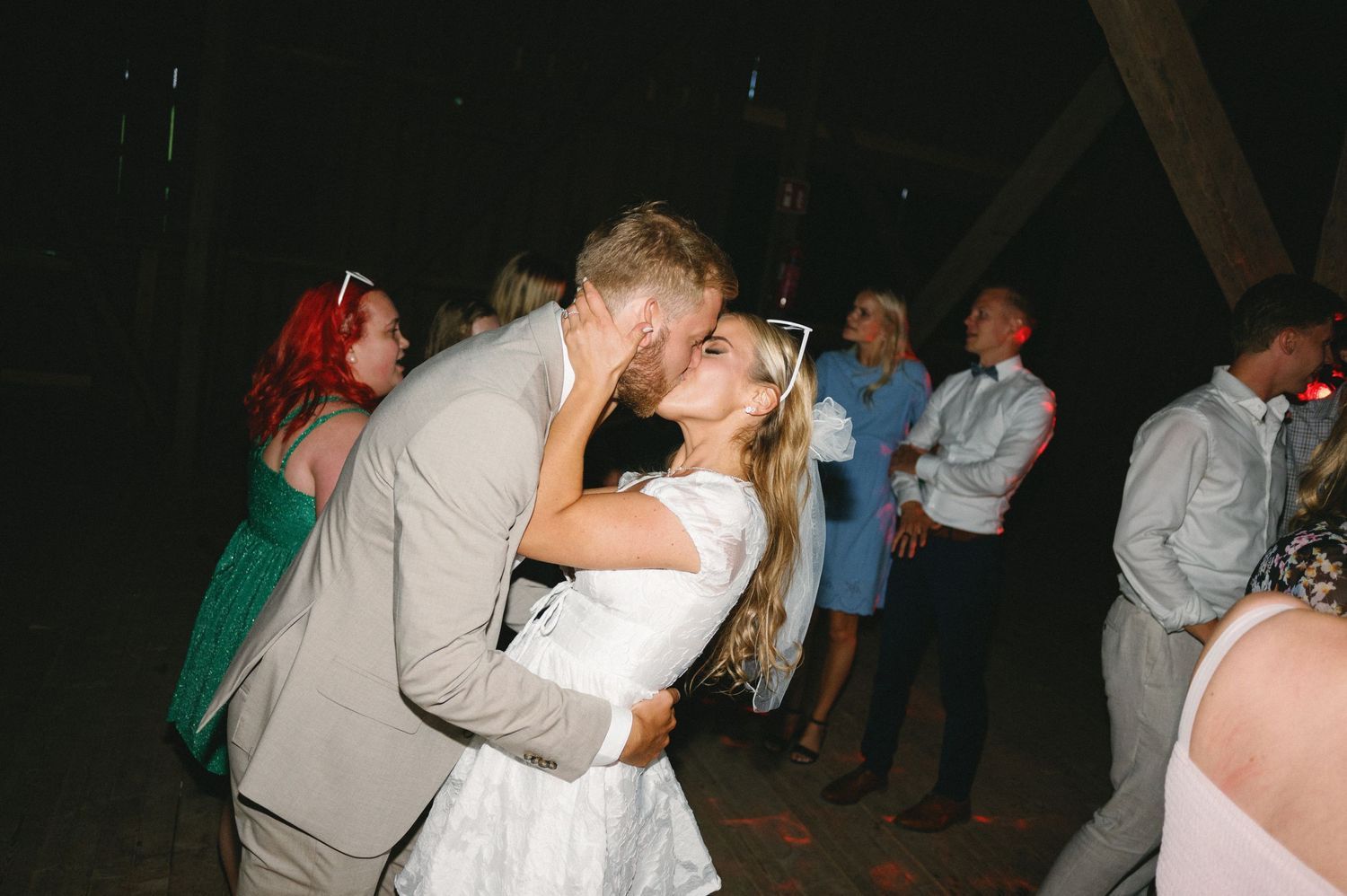 Wedding celebration with guests dancing in formal attire under string lights.