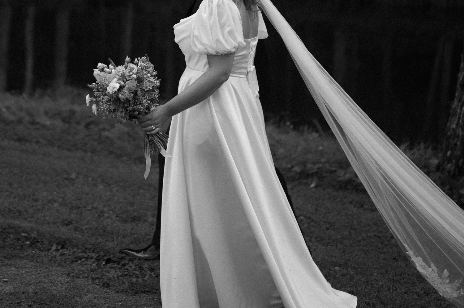 Elegant wedding dress with flowing train captured in black and white photography.