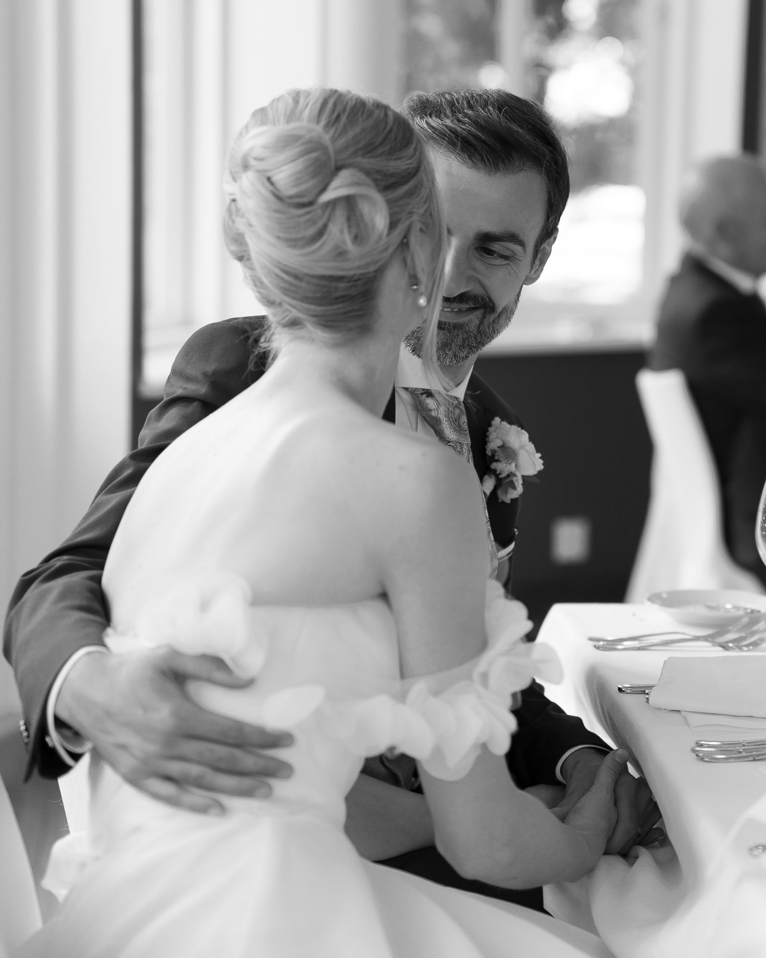 Black and white photo of a bride and groom sharing a tender embrace at their wedding reception.