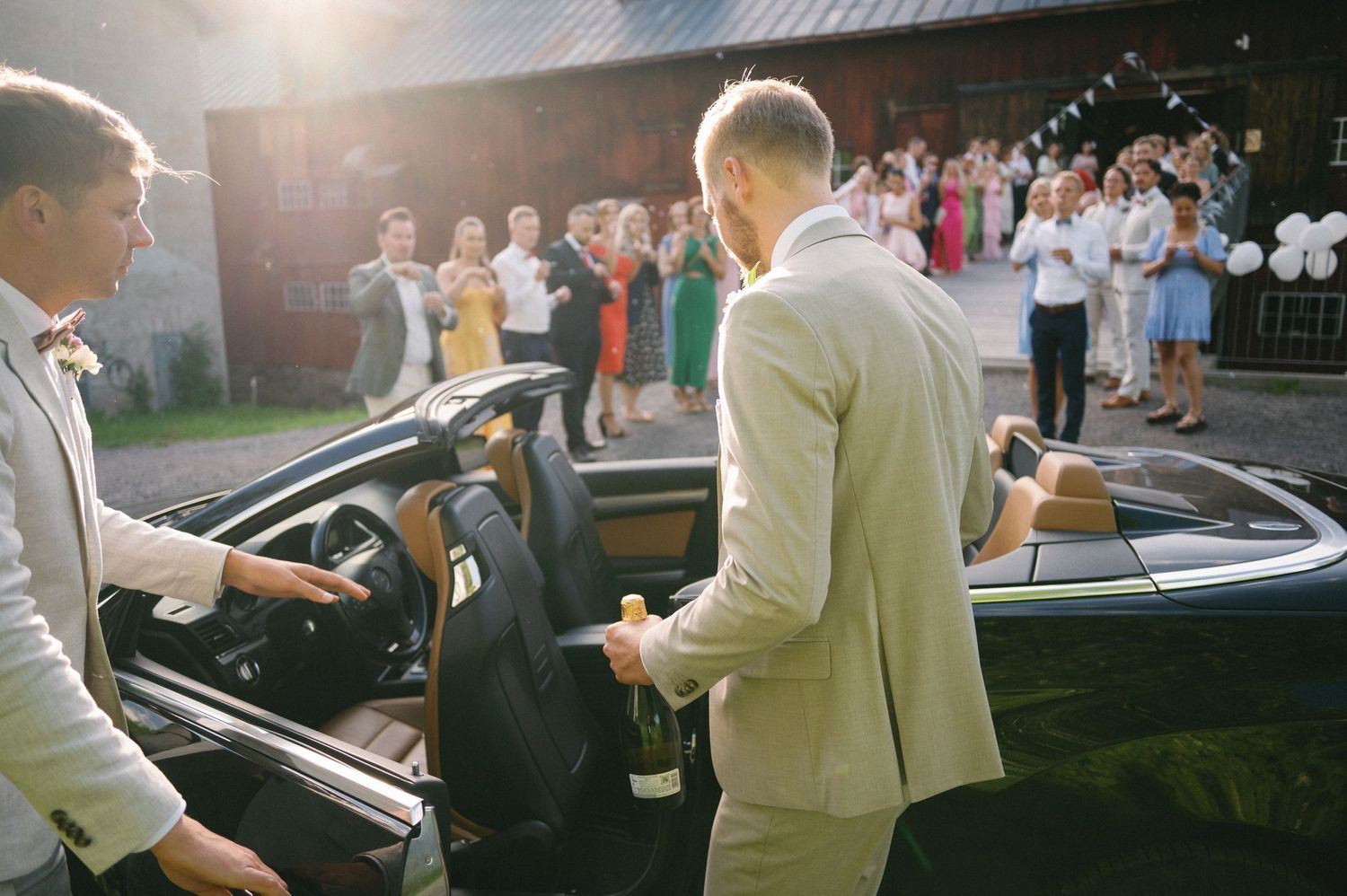 Vintage convertible car parked outside a rustic barn at a wedding celebration.