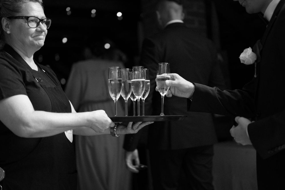 Service staff holding trays of champagne glasses at an event.