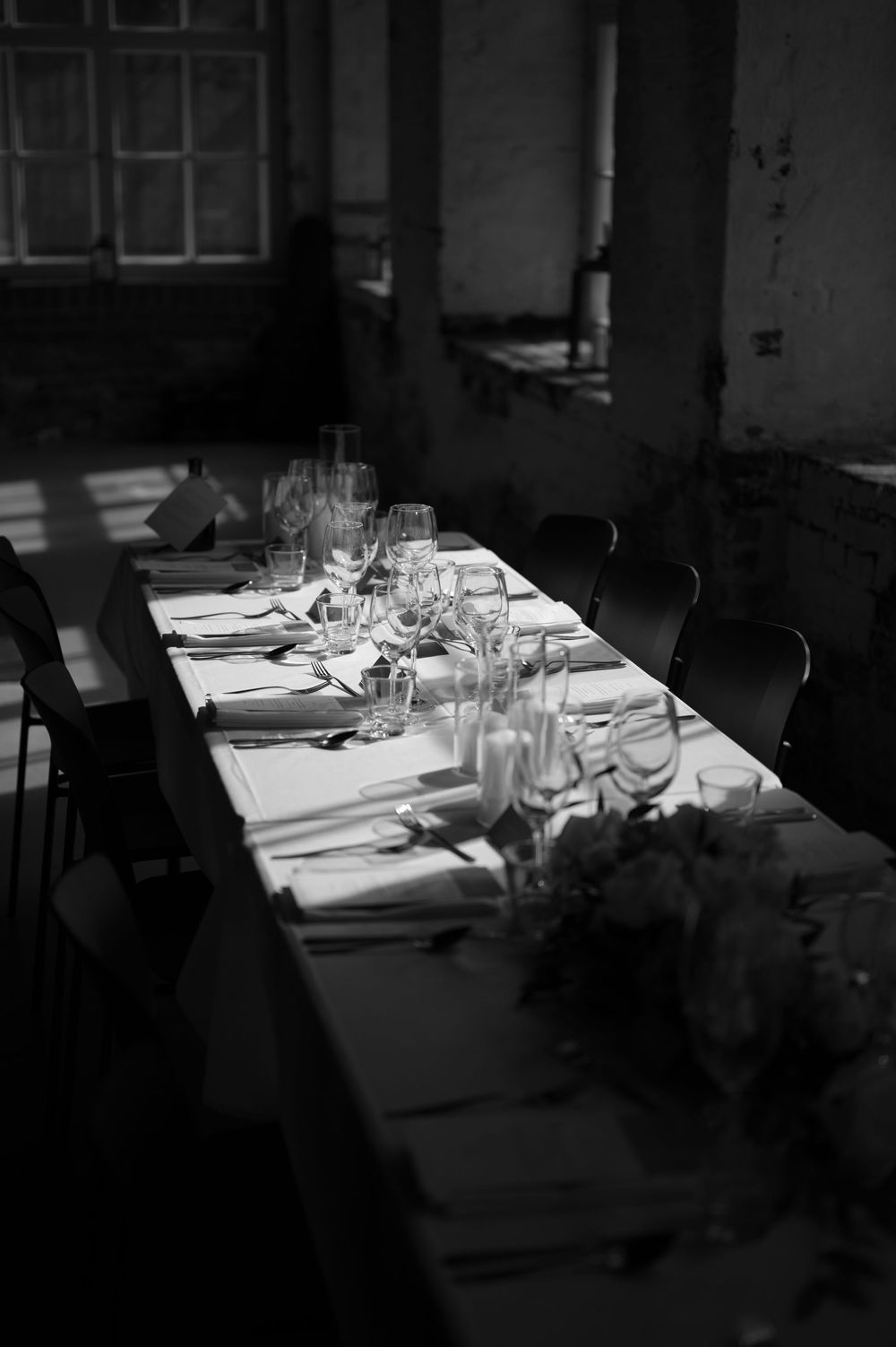 Sunlit dining tables arranged with formal place settings in a minimalist space.