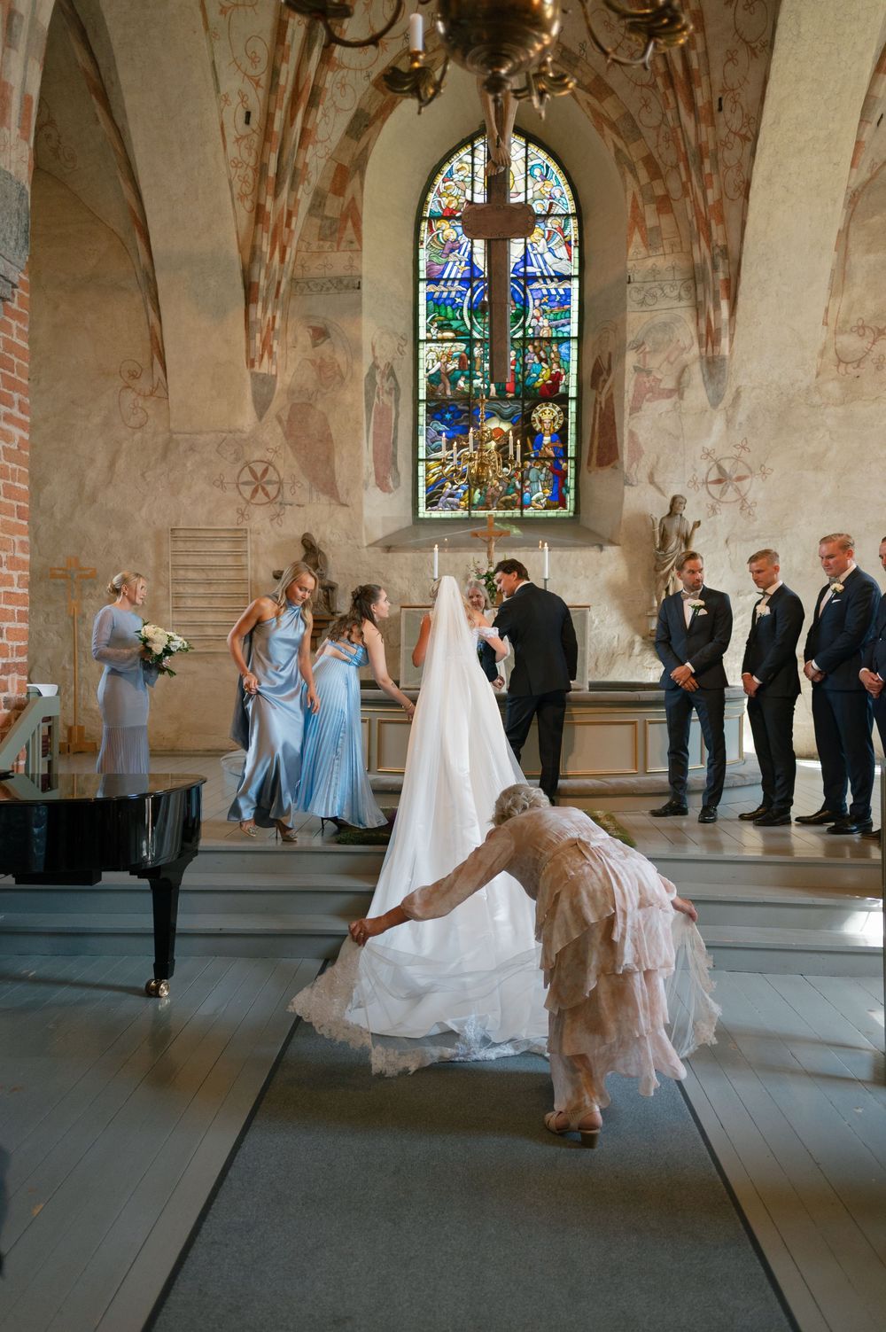 Wedding party gathered in a historic church with stained glass windows and vaulted architecture.