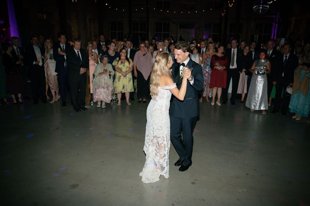 Wedding reception dance floor with string lights and purple accent lighting overhead.